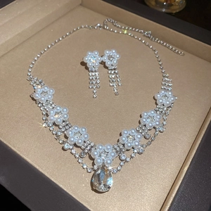 Detailed view of crystal flower and waterdrop pearl jewelry set inside a beige gift box