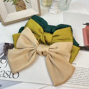Detailed trio of satin bow hair clips in forest green, ginger yellow, and champagne silk