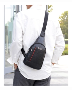 Men's black PU leather sling bag with metal logo and red stripe detail worn on back