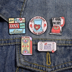 Set of 5 retro pink enamel pins featuring telephone and matchbox designs on denim