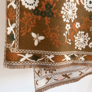 Close-up of brown cashmere-like scarf with orange floral patterns and fringed edges
