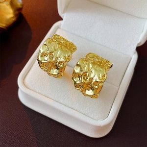 Irregular gold pleated C-shaped stud earrings displayed in a white velvet jewelry box