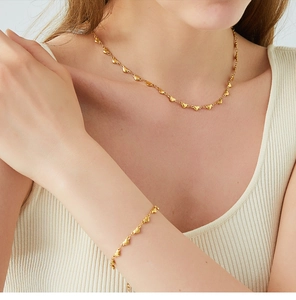 Close-up of 18K gold plated heart link necklace and bracelet set on model skin