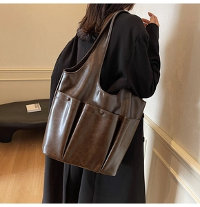 Detail of dark brown PU leather tote bag featuring dual front pockets and soft texture