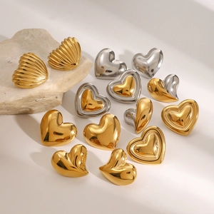 Detailed view of heart-shaped and shell-style gold and silver earrings on a stone