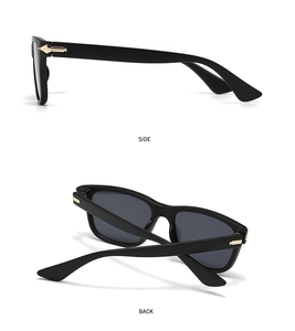Detail view of round black sunglasses with grey lenses and golden metal hinge accents