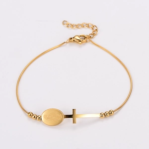 Close-up of golden religious bracelet featuring Virgin Mary medal and cross pendants
