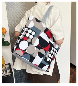 Detail view of large canvas tote bag featuring geometric print and grey fabric shoulder strap