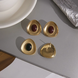 Detail of vintage geometric earrings with red and green stones and matte gold brushed finish