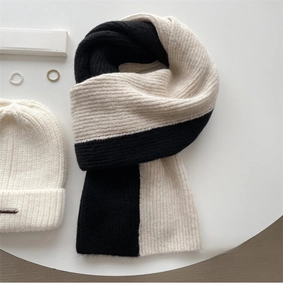 Close-up of black and white color-block knit scarf with decorative woven label detail