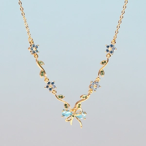 Elegant gold necklace featuring blue and green floral charms and butterfly accents