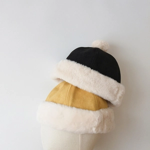 Detail of warm winter faux fur hats in black and mustard yellow with soft suede texture
