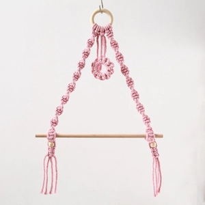 Detail of pink macrame toilet paper holder with natural wood rings and fringe tassel