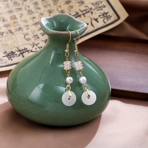Detail of Chinese tassel earrings with pearls and jade-like rings on a ceramic vase