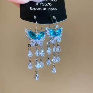 Detailed close-up of butterfly earrings with blue crystals and silver-plated tassels