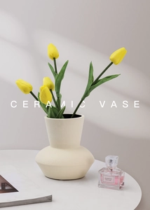 Detailed macro view of cream ceramic vase with matte finish and yellow tulips