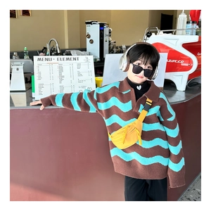 Detail of child wearing a bright yellow nylon chest bag with a striped polo sweater