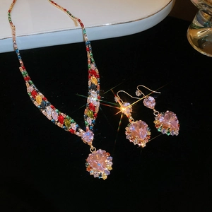 Detail showing gold necklace and earrings with pink heart gems and colorful square stones