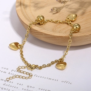 Vue détaillée d'une chevillère en acier doré avec pendentifs cœur et perles sur bois