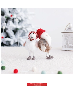 Detail of two handmade Christmas wool felt Santa dolls with red knit hats on soft fur