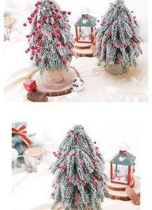 Close-up of artificial desktop Christmas tree with red berries, snow, and burlap base
