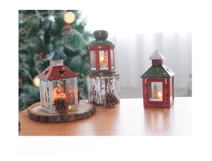 Close-up of three vintage Christmas iron lanterns in red, green, and white on wood base