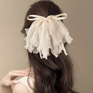 Elegant off-white tulle bow hair claw clip with pearls on wavy brown hair