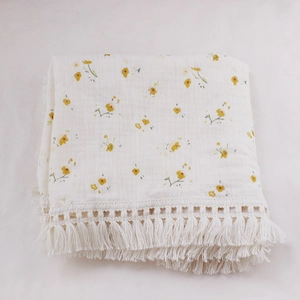 Close-up of baby double-layer cotton blanket with floral print and fringe details