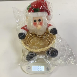 Detailed view of Santa Claus themed candy basket on scale showing 62.1g weight