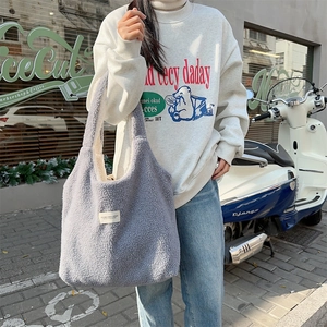 Detail of light gray plush tote bag featuring soft fleece texture and woven brand label