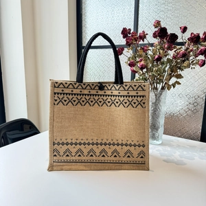 Detail of jute tote bag with ethnic geometric patterns and black braided handles
