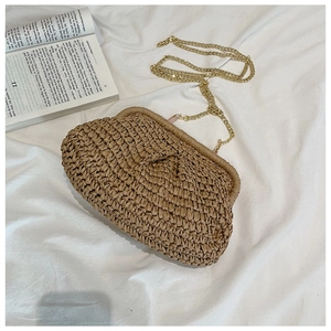 Detail of straw woven crossbody bag with gold chain strap on a white sheet