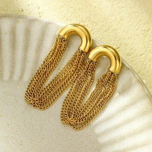 Detail view of golden U-shaped stud earrings with long metal chain tassels and polished finish