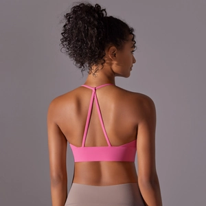 Detail view of pink sports bra featuring cross-back thin straps and elastic wide hem