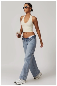 Detailansicht eines cremeweißen Halter-Yoga-BHs kombiniert mit lässiger Denim-Jeans