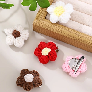 Detail of five colorful knitted flower hair clips with metal duckbill clips on wood decor