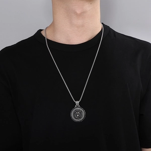 Detail of silver stainless steel lion head pendant necklace worn on a black t-shirt