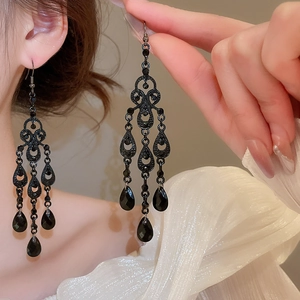 Detailed view of elegant hollow teardrop earrings with black gems on a female model