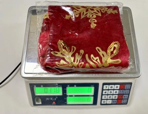 Macro view of red velvet Christmas stocking with gold embroidery on a digital scale