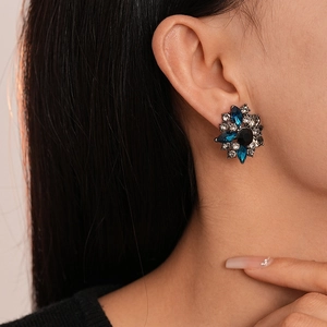 Close-up of vintage flower stud earrings with dark blue and grey crystals on a model