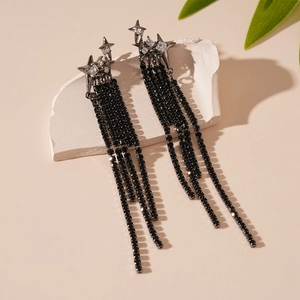 Macro shot of silver needle star earrings with hanging black zircon tassels on white stone