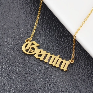 Macro shot of gold Gemma name necklace with Old English font and fine O-chain detail