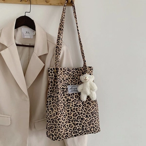 Detailed view of leopard print canvas tote bag with a cute plush bear charm accessory