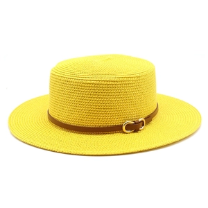 Détail d'un chapeau de paille jaune plat avec bandeau en cuir brun et boucle dorée