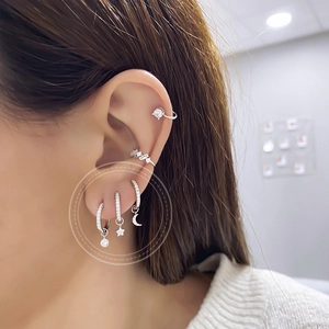 Detailed view of S925 silver earrings set with moon, star and zircon pendants on model