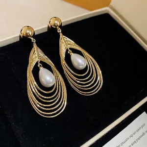 Elegante goldene Tropfenohrringe mit Perlen auf schwarzem Samt im Schmuckkästchen