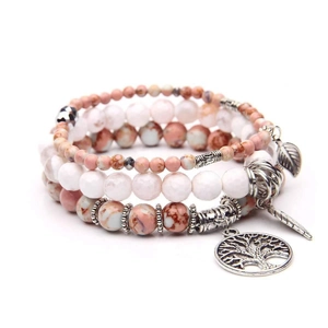 Detail of layered bohemian bracelet featuring tree of life, feather pendants and beads