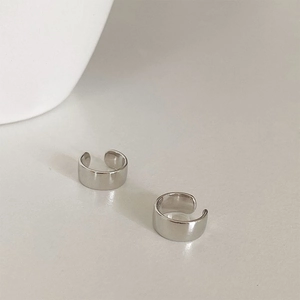 Detailed view of two polished silver metal multi-layer ear cuffs on white surface