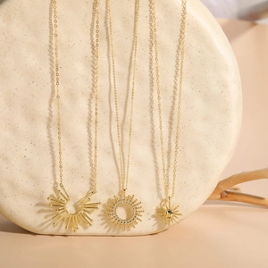 Close-up of three gold sunflower and starburst necklaces on a textured stone stand