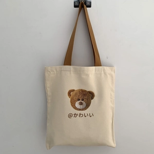 Detail of canvas tote bag with brown handles and cute bear print design